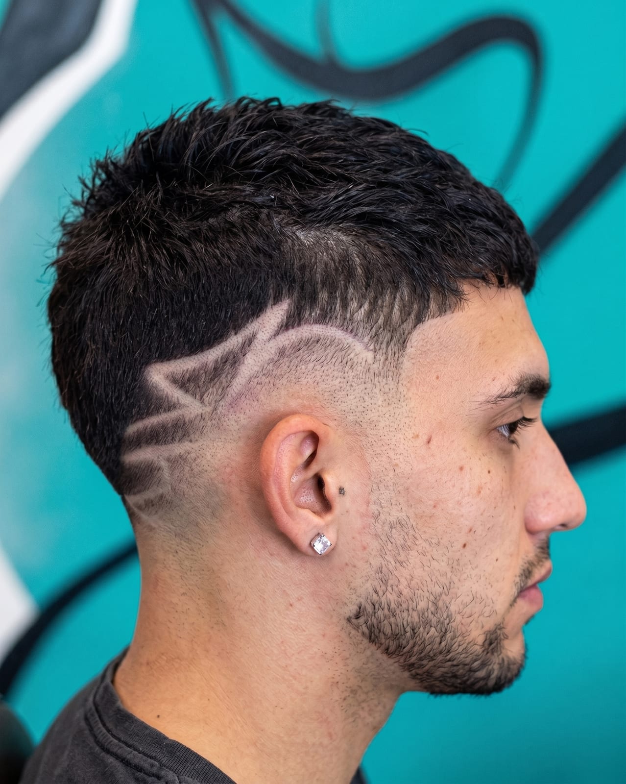 Fade sfumato con disegno rasurato sulla tempia e barba curata